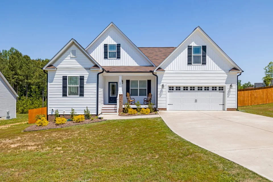 A concrete driveway approaching a white suburban home